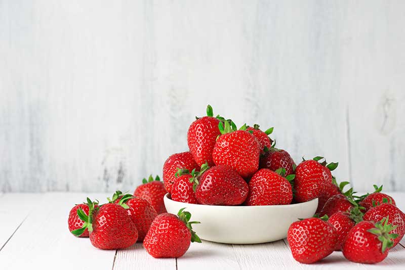 Fresh strawberries in a vibrant arrangement, showcasing their juicy red color and lush texture.