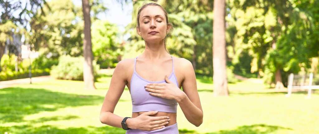 Person practicing deep breathing outdoors, enhancing lung capacity with focused exercises.
