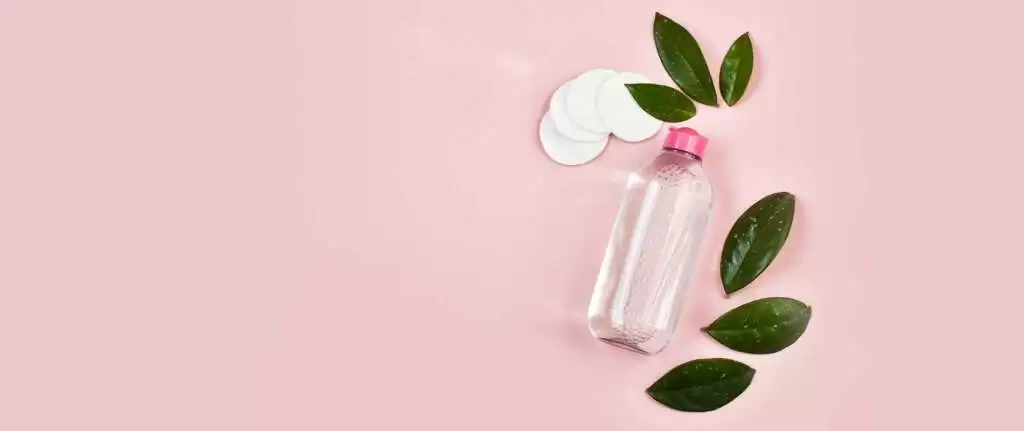 Natural homemade face toners in glass bottles with fresh ingredients like herbs and flowers