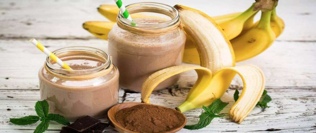 Chocolate Banana Smoothie in a glass topped with fresh banana slices and chocolate shavings